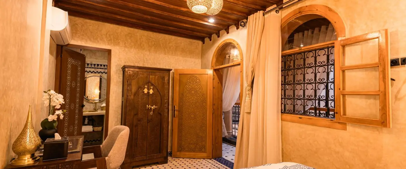 Une chambre, la fenêtre en bois ouverte sur la galerie