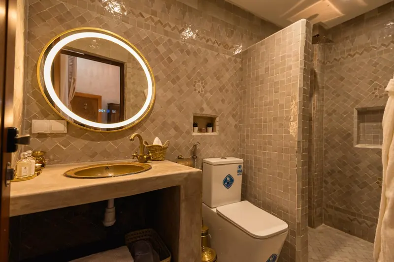 Une salle de bains, le miroir rond et la vasque en laiton